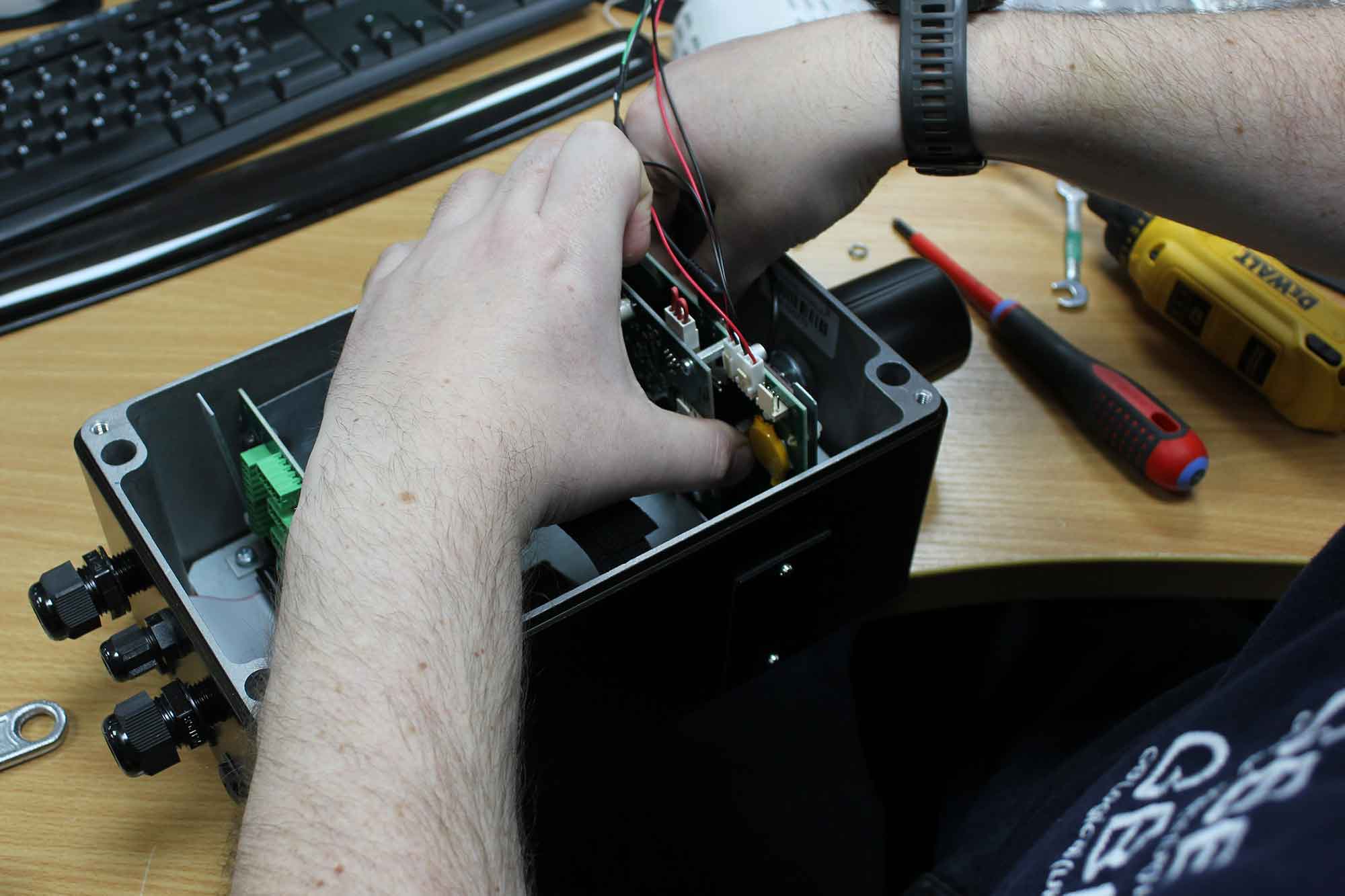 A close up of hands placing a PCB inside an outer casing.